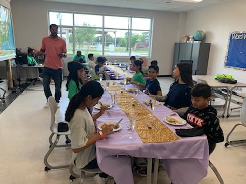 kids sitting on long table in classroom setting