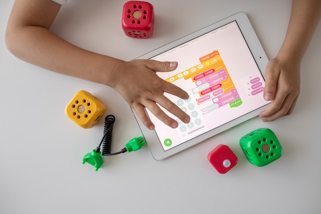 over head shot of a child's hands on a laptop surrounded by toy blocks